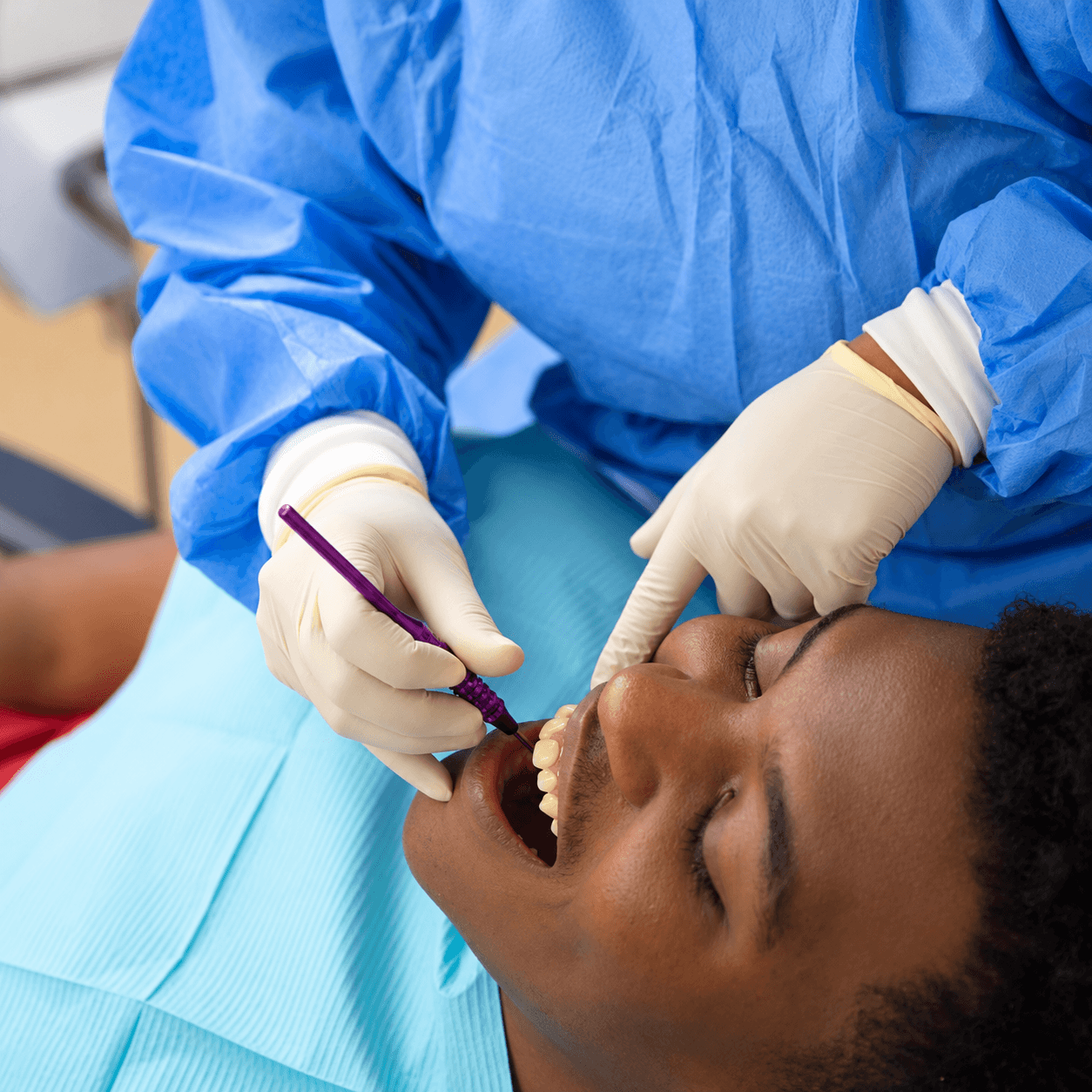 Un paciente recibe atención odontológica con instrumental dental y guantes.